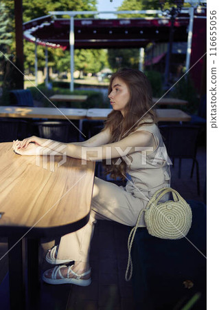 a  beautiful teenage girl in a peach fuzz suit with a vest, in the old money style in a fancy restaurant 116655056