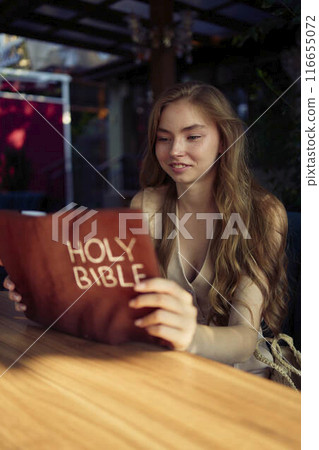 beautiful teenage girl in a peach fluffy suit with a waistcoat in the old money  style reads the Holy Bible and prays 116655072