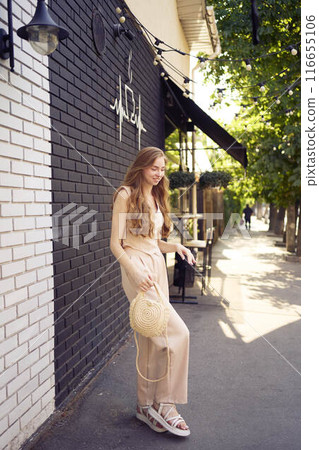 a beautiful teenage girl in a peach fuzz suit with a waistcoat, in the old money style walks through the morning city a beautiful teenage girl in a peach fuzz suit with a waistcoat, in the old money style walks through the morning city 116655106
