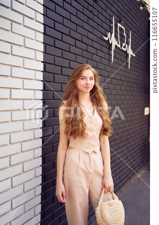a beautiful teenage girl in a peach fuzz suit with a waistcoat, in the old money style walks through the morning city a beautiful teenage girl in a peach fuzz suit with a waistcoat, in the old money style walks through the morning city 116655107