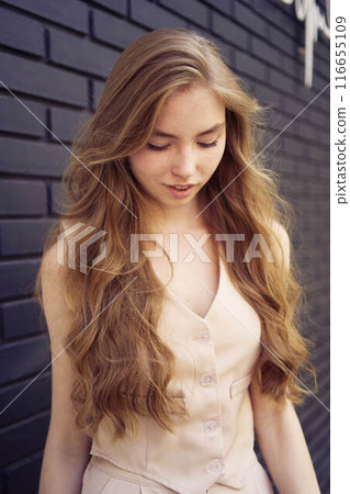 a  beautiful teenage girl in a peach fuzz suit with a waistcoat, in the old money style  walks through the morning city 116655109