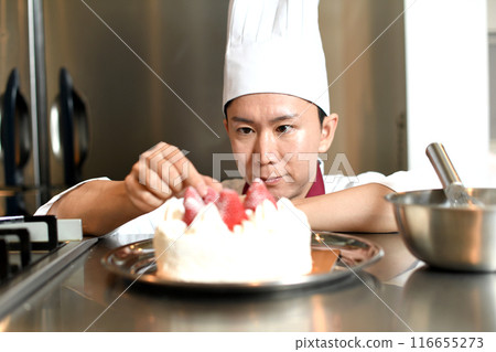 A male pastry chef making a whole cake 116655273