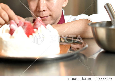 A male pastry chef making a whole cake A male pastry chef making a whole cake 116655276