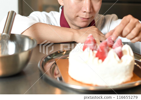 A male pastry chef making a whole cake 116655279