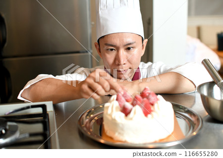 A male pastry chef making a whole cake 116655280