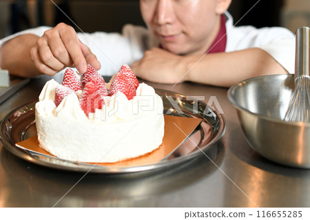 A male pastry chef making a whole cake A male pastry chef making a whole cake 116655285