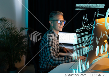 Smiling Man Analyzing Data on Computer Screen in Office 116656120