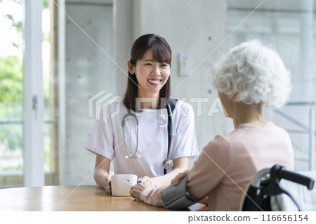 Nurse measuring blood pressure of a senior woman 116656154