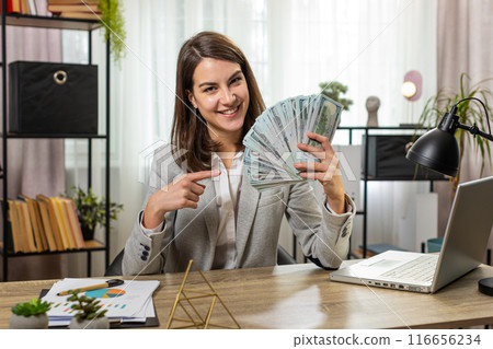 Smiling businesswoman counting cash money dollar checking salary enjoy richness at home office table Smiling businesswoman counting cash money dollar checking salary enjoy richness at home office table 116656234