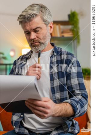 Mature man with documents analyzing information reading business papers prepare financial report 116656295