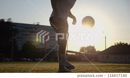 Legs of young man kicking ball at green field. Male feet of professional footballer juggling soccer ball on stadium at sunset. Sportsman practicing tricks outdoor. Concept of a freestyle football Legs of young man kicking ball at green field. Male feet of professional footballer juggling soccer ball on stadium at sunset. Sportsman practicing tricks outdoor. Concept of a freestyle football 116657180