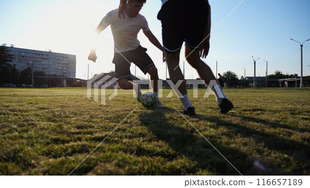 Two sportsmen playing in soccer in stadium at sunset. Professional footballers performing tricks with ball at green field. Young men training at meadow. Concept of a freestyle football. Slow motion 116657189