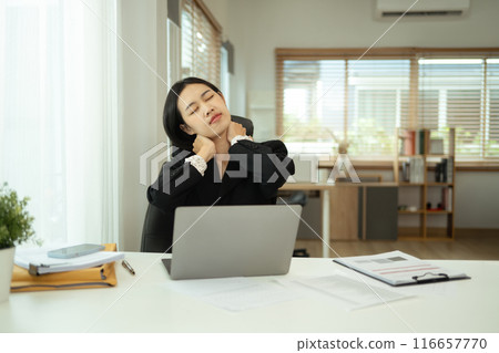 Tired young businesswoman massaging her neck and shoulders, indicating fatigue or muscle tension Tired young businesswoman massaging her neck and shoulders, indicating fatigue or muscle tension 116657770