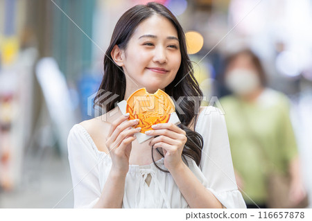 A young woman eating while sightseeing 116657878