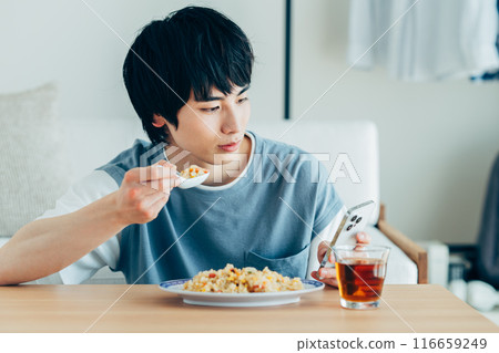 年輕人一邊吃炒飯一邊看智慧型手機 116659249