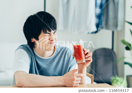 A young man drinking vegetable juice 116659317