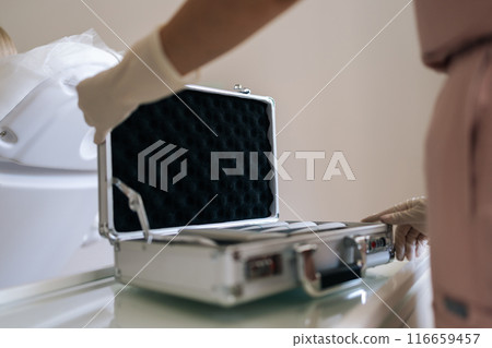 Closeup cropped shot of unrecognizable trichologist opening suitcase with device preparing for wellness procedure at medical clinic. Concept of general checkup, healthcare, insurance. 116659457