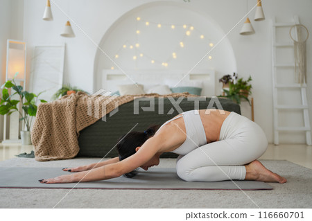 Yoga fitness workout training. Woman practicing yoga at home. Woman doing sports exercise on yoga mat on floor indoor. Girl in sportswear have training workout for weight loss. Sport and fitness Yoga fitness workout training. Woman practicing yoga at home. Woman doing sports exercise on yoga mat on floor indoor. Girl in sportswear have training workout for weight loss. Sport and fitness 116660701