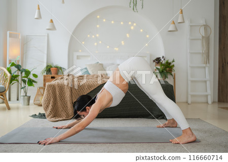 Yoga fitness workout training. Woman practicing yoga at home. Woman doing sports exercise on yoga mat on floor indoor. Girl in sportswear have training workout for weight loss. Sport and fitness 116660714