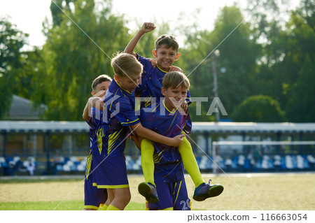 Smiling friends, boys jumping and hugging, expressing happiness and excitement after winning soccer game on outdoor stadium Smiling friends, boys jumping and hugging, expressing happiness and excitement after winning soccer game on outdoor stadium 116663054