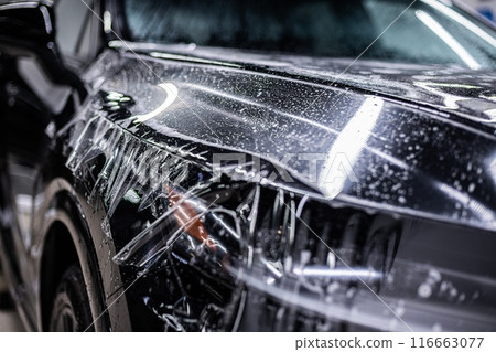 Applying PPF Paint Protection Film on car hood, ensuring protection and glossy finish 116663077