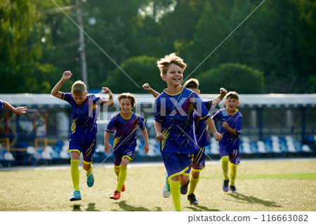 Happy and excited boys, children in sportswear running on field, expressing happiness and success after winning match. Team spirit. 116663082