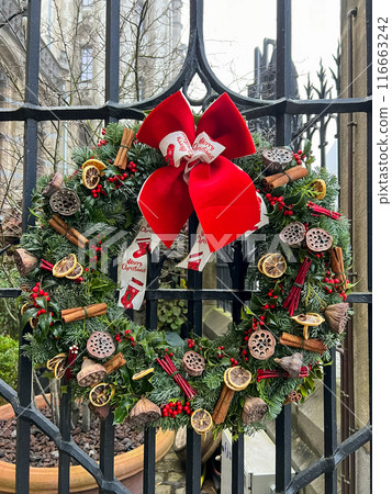 Festive christmas wreath hanging on a beautifully ornate metal gate Festive christmas wreath hanging on a beautifully ornate metal gate 116663242