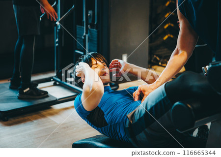 一名男子在健身房接受教練的指導 一名男子在健身房接受教練的指導 116665344