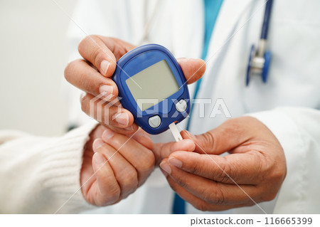 Asian doctor using digital glucose meter for check sample blood sugar level to treatment diabetes. Asian doctor using digital glucose meter for check sample blood sugar level to treatment diabetes. 116665399