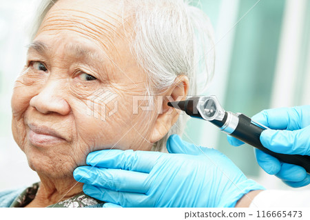 Otolaryngologist or ENT physician doctor examining senior patient ear with otoscope, hearing loss problem. Otolaryngologist or ENT physician doctor examining senior patient ear with otoscope, hearing loss problem. 116665473