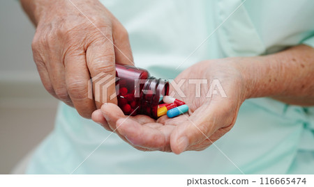 Asian elderly woman holding pill drug in hand, strong healthy medical concept. Asian elderly woman holding pill drug in hand, strong healthy medical concept. 116665474