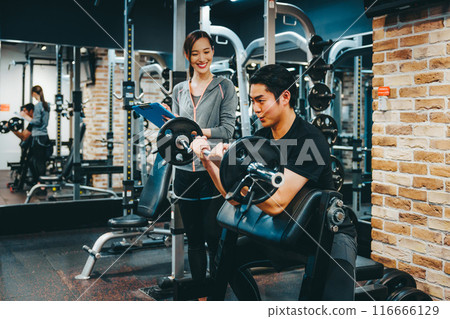 A man receiving guidance from a trainer at a fitness gym 116666129