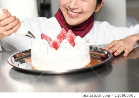 A female pastry chef preparing a whole cake 116666503