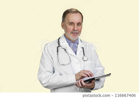 Aged senior male doctor holding digital tablet in hands. Isolated on white. 116667406