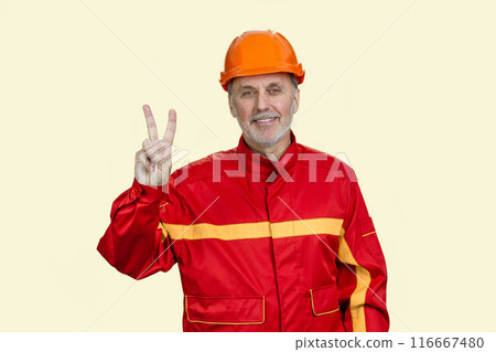Happy smiling construction worker shows victory gesture sign. Isolated on white. 116667480