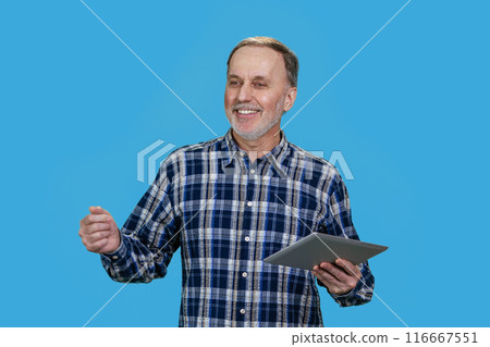 Portrait of a handsome cheerful smiling senior man holding tablet pc device. Isolated on blue background. 116667551
