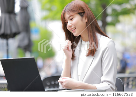 在一座綠樹成蔭的城市裡,女商人微笑著看著筆記型電腦_1 在一座綠樹成蔭的城市裡,女商人微笑著看著筆記型電腦_1 116667558