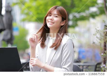 在一座綠樹成蔭的城市裡,女商人微笑著打開筆記型電腦_1 在一座綠樹成蔭的城市裡,女商人微笑著打開筆記型電腦_1 116667559