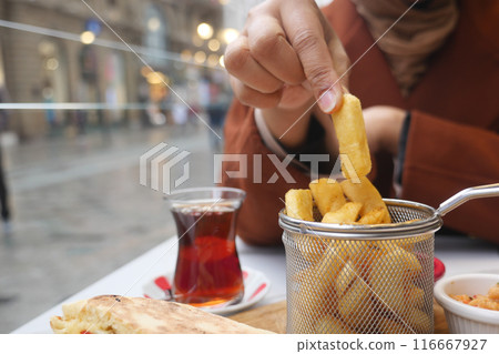 woman hand pick French Fries sitting on outdoor cafe woman hand pick French Fries sitting on outdoor cafe 116667927