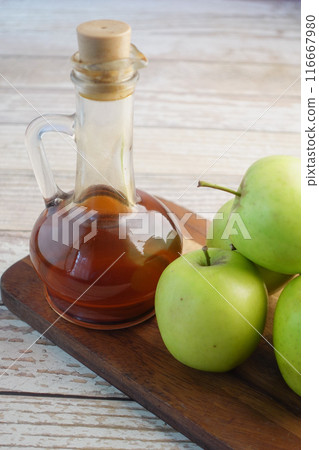 apple vinegar in glass bottle with fresh green apple on table  116667980