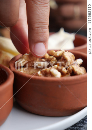 woman hand pick walnuts from a bowl woman hand pick walnuts from a bowl 116668110