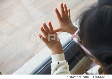 A childs hands are gently touching the glass, full of curiosity and wonder of early childhood 116668308