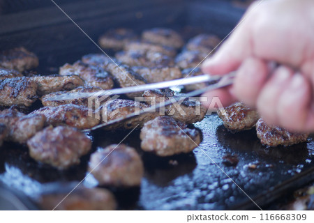 Eating delicious beef patties on a grill with backyard BBQ, burgers, and summer cookouts 116668309