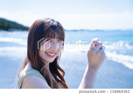 A woman photographing the sea with a compact digital camera 116668362