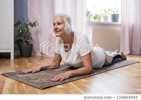 Elderly woman doing pilates on mat at home 116668988