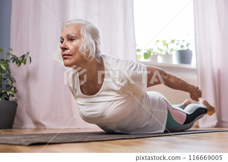 Elderly woman doing pilates on mat at home 116669005