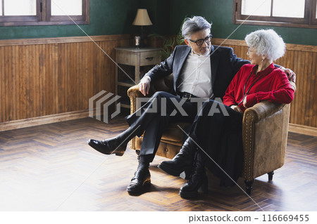 Grey-haired couple sitting on a sofa Grey-haired couple sitting on a sofa 116669455