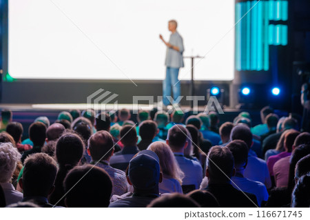 Speaker presenting to a large audience in a conference hall 116671745