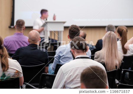 Audience attending tech conference listening to speaker presentation Audience attending tech conference listening to speaker presentation 116671837