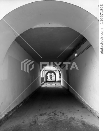 Black and white tunnel view with arches and person in distance Black and white tunnel view with arches and person in distance 116671898